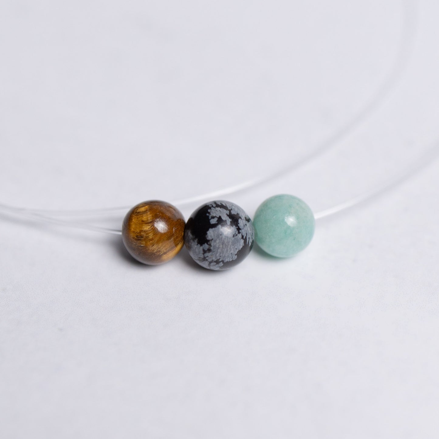 Human Design Kette Generator – Amazonit, Schneeflockenobsidian und Tigerauge auf transparentem Nylonband mit 6mm Perle