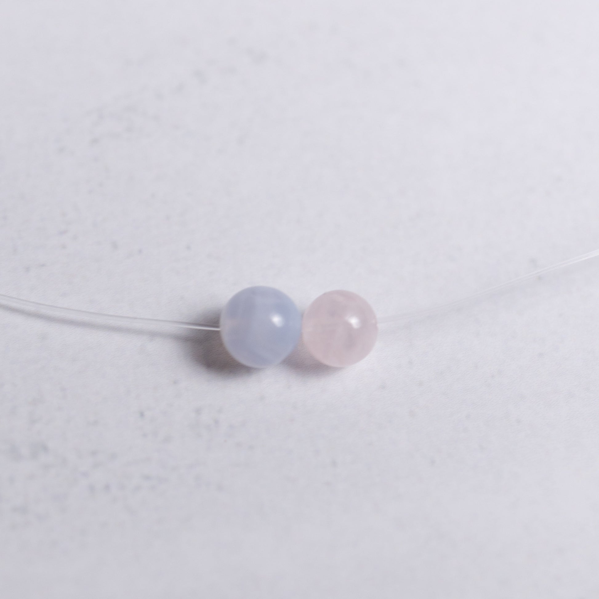 Selbstliebe Kette mit transparentem Nylonband und je einer 6mm Perle aus Rosenquarz und Chalcedon – minimalistischer Energieschmuck